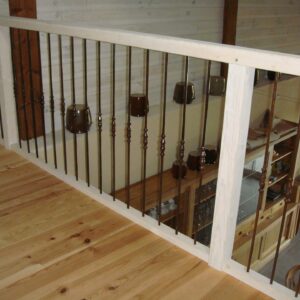 Balustrade bois clair et fer forgé sombre vue d'une mezzanine sur salon-cuisine, sol en pin clair.